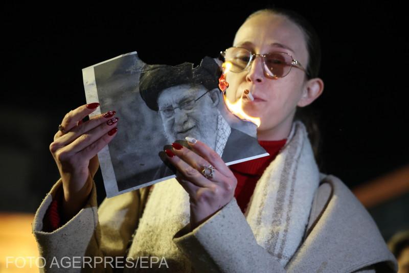 O femeie își aprinde simbolic o țigară cu focul aprins de la o imagine cu Ayatollahul Ali Khamenei. Sursa foto: Agerpres