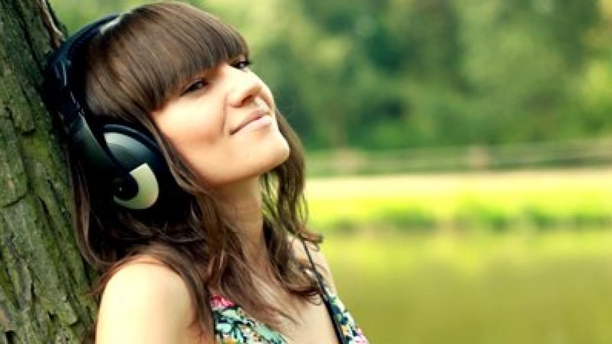 stock_footage_woman_with_headphones_listen_to_the_music_in_the_park_03979800