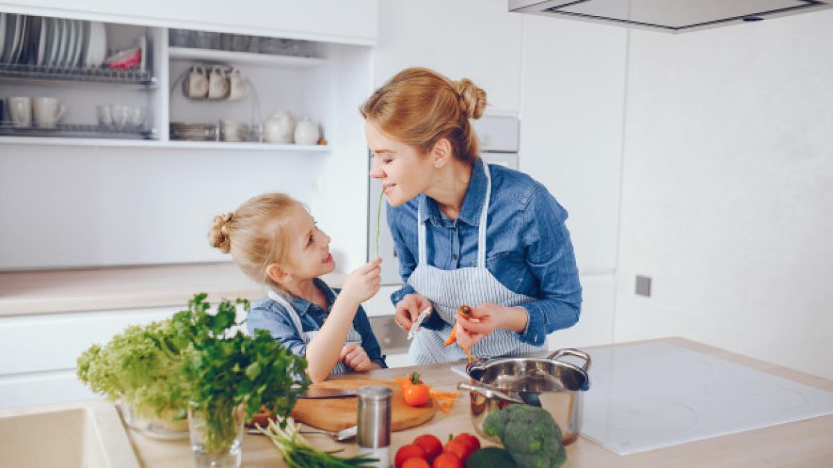 beautiful-mother-in-a-blue-shirt-and-apron-is-preparing-a-fresh-vegetabl---_41227200