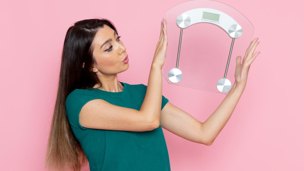 front-view-young-female-holding-scales-light-pink-wall-exercise-sport-workout-athlete-waist-beauty_71086400