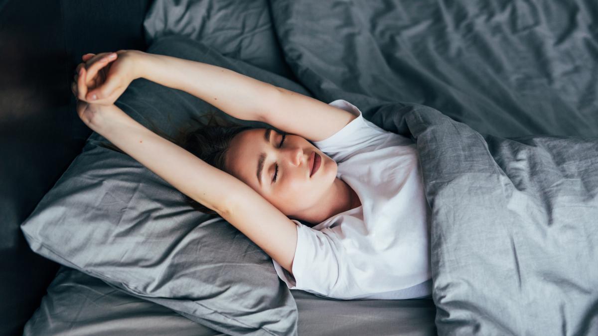 attractive-woman-stretching-morning-is-smiling-her-bed_99157200