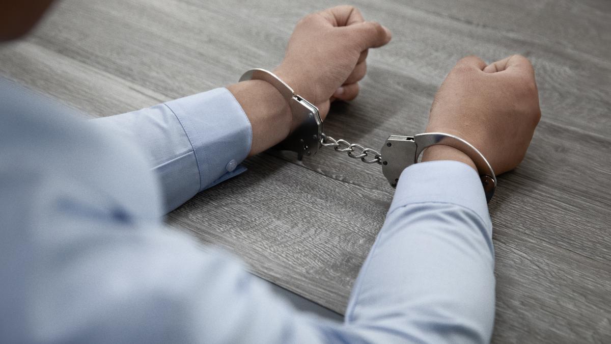 selective-focus-shot-male-hands-handcuffs-wooden-table_33013800