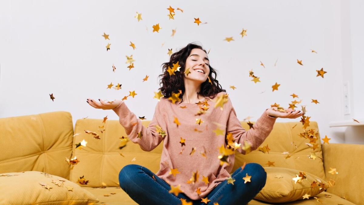 expressing-true-positive-emotions-young-joyful-woman-with-cut-curly-hair-having-fun-falling-tinsels-couch-modern-apartment-home-cosines-joy-smiling_197531-2232_09750900