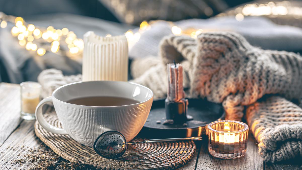 cozy-home-composition-with-cup-tea-candles-knitted-element_43614400