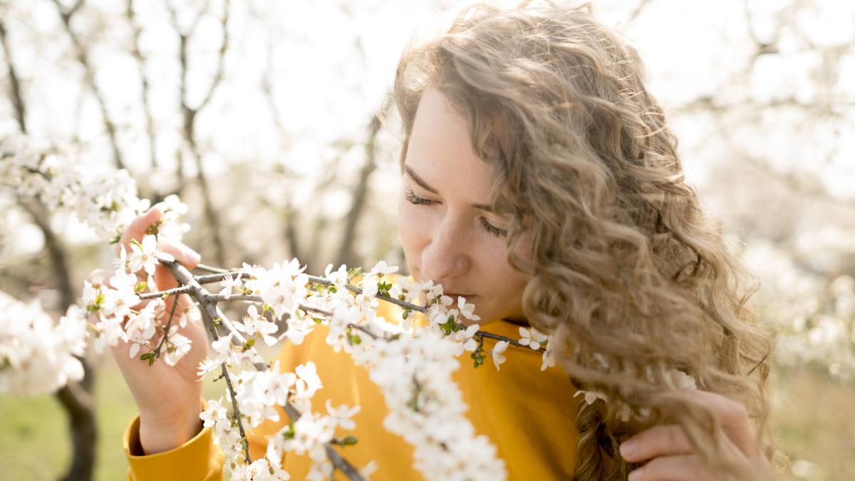 woman-wearing-yellow-shirt-smelling-flowers_03351900