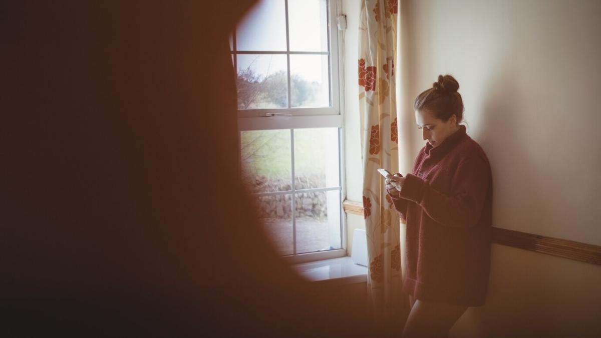woman-using-mobile-phone-near-window-home_107420-96291_10524000