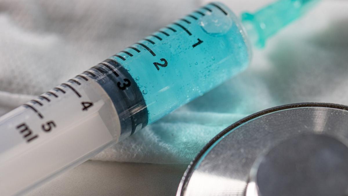 closeup-needle-syringe-with-blue-liquid-it-table-lights_181624-18425_79356200