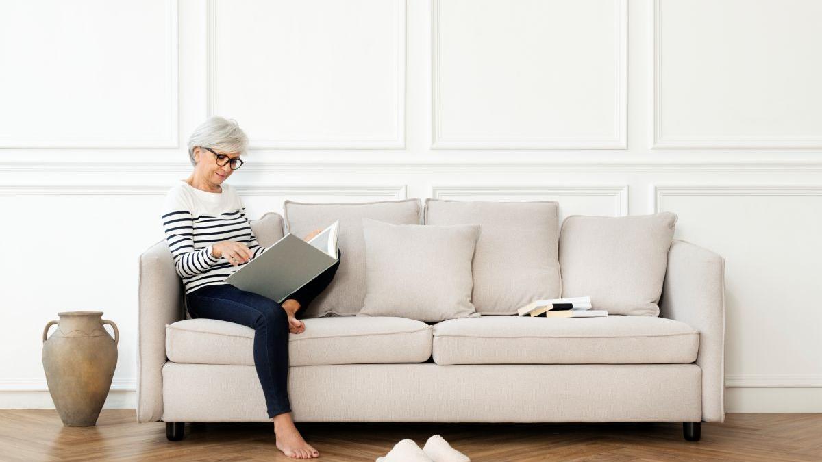 senior-woman-reading-book-sofa-scandinavian-decor-living-room_13587400