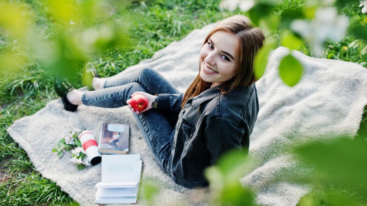 young-brunette-girl-jeans-sitting-plaid-against-spring-blossom-tree-read-book_71233200