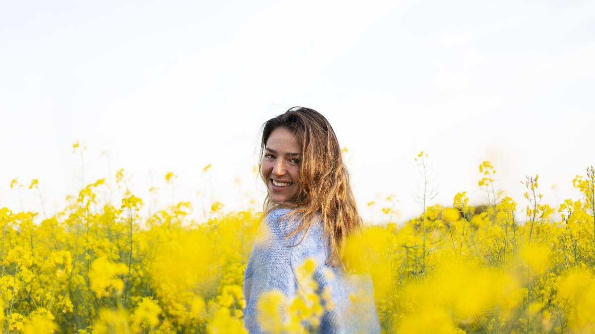 portrait-smiling-young-woman-with-yellow-flowers-field_39203100
