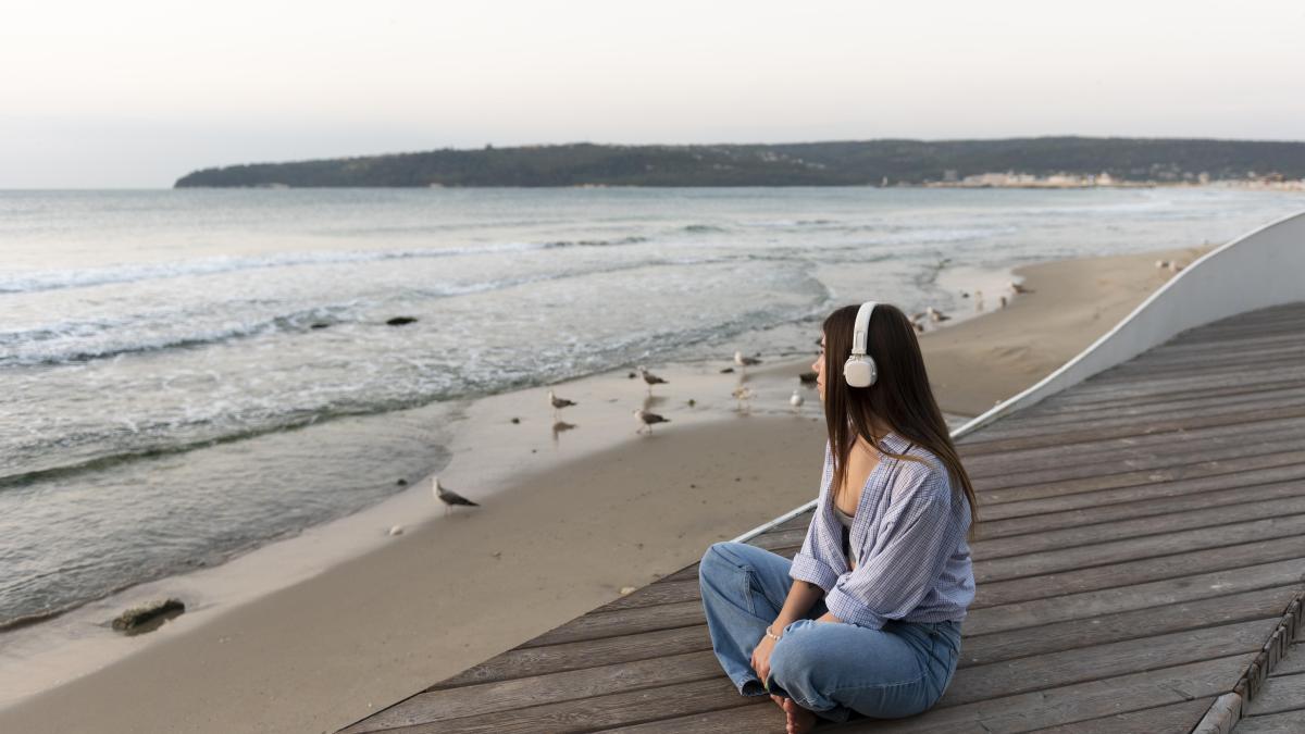 side-view-woman-listening-music-sea_82619500