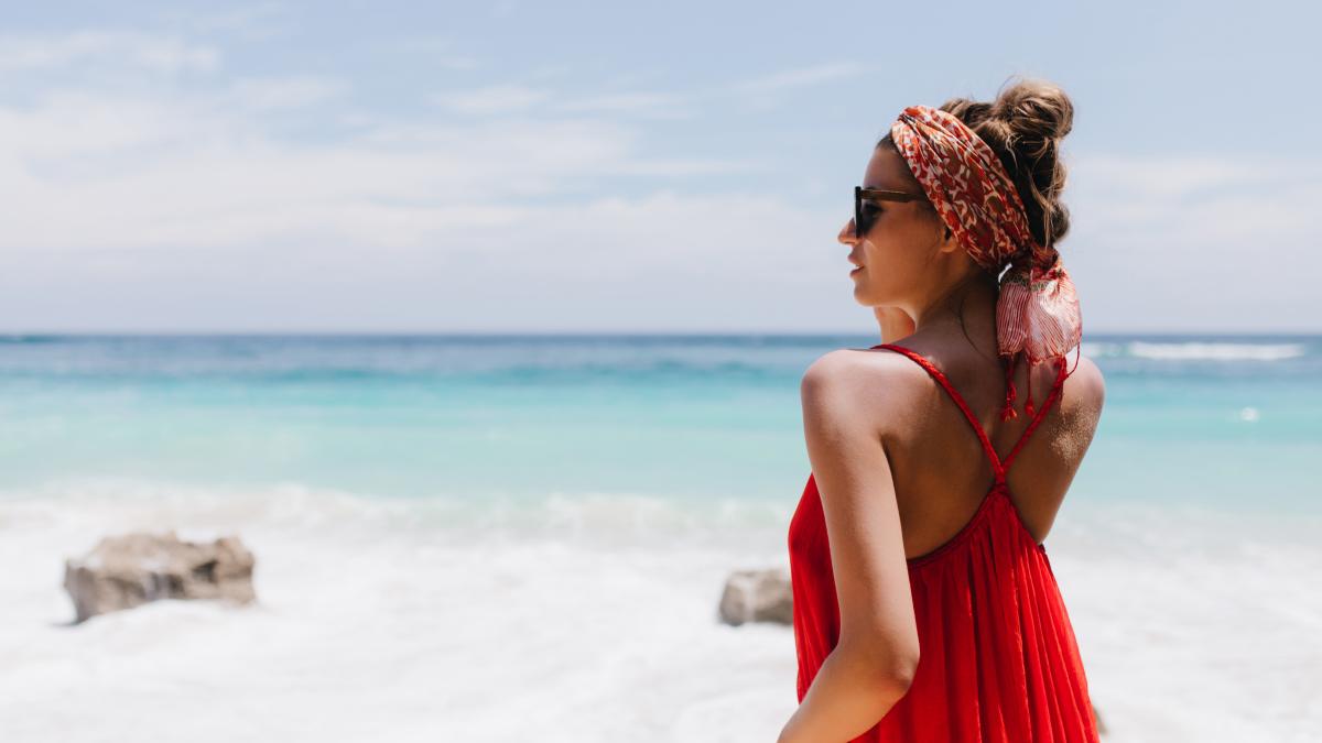 portrait-from-back-carefree-girl-with-tanned-skin-looking-horizon-photo-happy-caucasian-female-model-red-attire-chilling-ocean-coast-enjoying-view_06481500