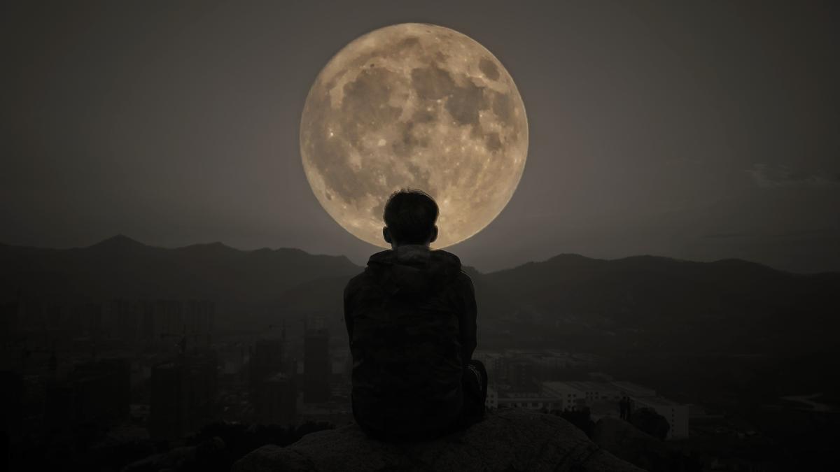 rear-view-silhouette-man-sitting-against-moon-night_79396000