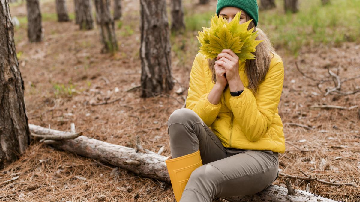 woman-covering-her-face-with-bunch-autumn-leaves