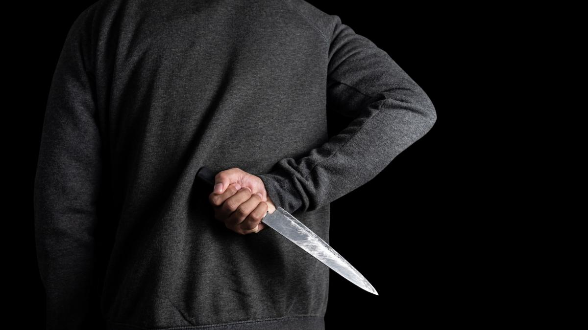 Imagine cu un bărbat care ascunde un cuțit la spate. Foto cu rol ilustrativ: Freepik