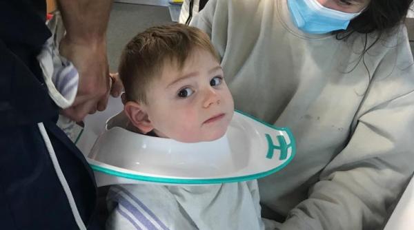 un copil a ramas cu un colac de toaleta prins in jurul capului