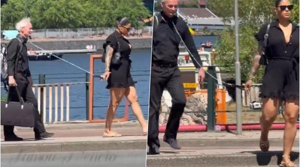 scena care a aprins internetul un barbat in varsta cu valiza plimbat in lesa pe strada de o femeie video